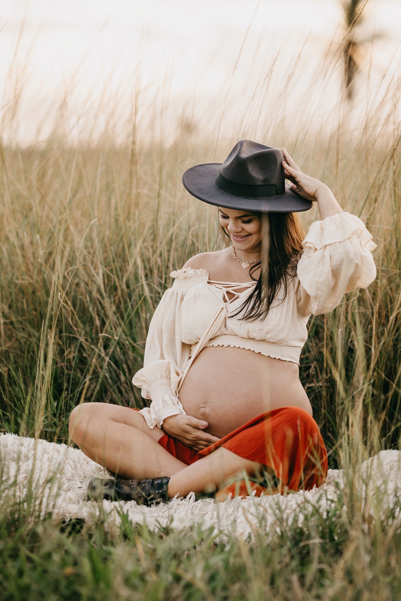 Pregant woman holding her belly wearing a hat